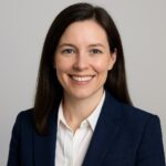A woman in a suit jacket and white blouse smiles confidently against a plain background, embodying the professionalism ideal for an elegant landing page.