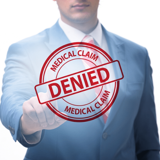 A man in a suit presses a virtual screen displaying a large red "DENIED" stamp over the words "MEDICAL CLAIM," highlighting challenges in revenue cycle management and the importance of tracking healthcare KPIs.